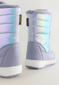 Lilla veekindlad saapad iridesentse pehme pihiku, faux karusnaha äärise ja tekstureeritud kummitaldadega; omavad reljeefset mäedisaini kandadel.