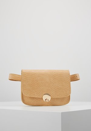 Sac à ceinture en simili cuir serpent beige avec un rabat et une fermeture à tourniquet dorée ronde, exposé sur un piédestal blanc.