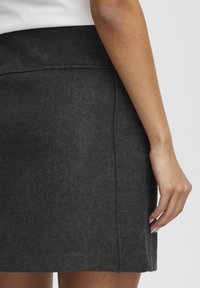 Grå minikjol i mjukt material med en ren design och rak silhuett, kompletterad med sidsömmar och en platt midja.