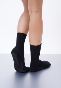 Schwarze Baumwollsocken mit einem gerippten Bund, knöchellang und mit gedruckten Größenangaben auf den Sohlen. Glatte Textur und angenehme Passform.