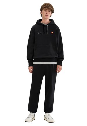 Sudadera con capucha negra hecha de mezcla de algodón, con bolsillo tipo canguro y logo bordado. Combinada con pantalones jogger negros a juego y zapatillas.