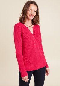 Gestrickter Pullover mit langen Ärmeln in leuchtendem Pink, mit tiefem V-Ausschnitt und Knopfdetails. Verfügt über eine strukturierte Rippstruktur und eine taillierte Silhouette.