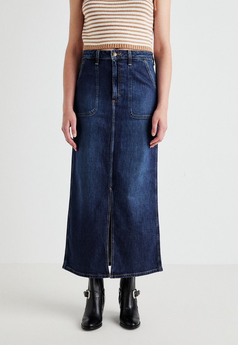 Jeans maksi krilo ima temno pranje, sprednji razporek, dva velika sprednja žepa in kontrastne šive. Ujemajo se z črnimi gležnjarji.