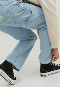 Ljusblå denimjeans med en avslappnad passform, med fem fickor och en lapp på bakfickan. Svarta högtoppssneakers med vita sulor.