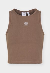 Brun ribbad crop top med rund halsringning och utan ärmar. Har en vit Adidas-logga på bröstet. Mjuk textur.