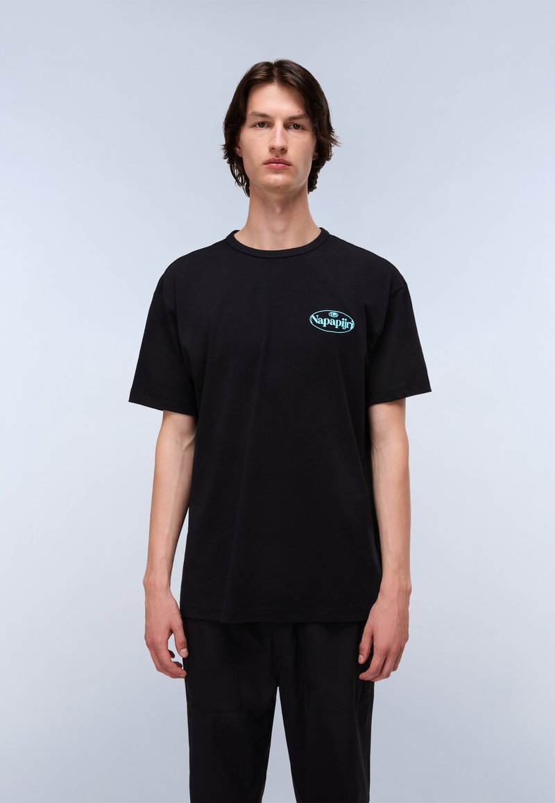 Sort bomulds t-shirt med rund halsudskæring, korte ærmer og et teal logo på venstre bryst. Modellen står foran en lysegrå baggrund.