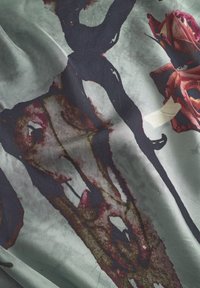 Silke med et mørkt abstrakt design med røde roser, en grønblå baggrund og forskellige teksturer, der skaber dybde og kontrast.