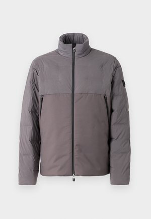 Giacca imbottita grigia con colletto alto, chiusura frontale con zip, due tasche con zip e design del pannello superiore a contrasto.