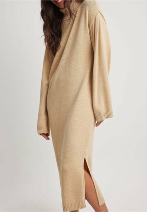 Beige oversized sweaterkjole med strikket struktur, høj halsudskæring, lange ærmer, sideslids, længde til midt på læggen, løs pasform.