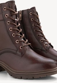 Stivali alla caviglia in pelle marrone con una finitura testurizzata, dotati di occhielli metallici, design con lacci e cerniera laterale per una facile calzata.