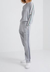 Ensemble de sweat-shirt et pantalon de survêtement gris, présentant des rayures multicolores le long des manches et sur le côté, fabriqué en tissu doux avec une coupe décontractée.