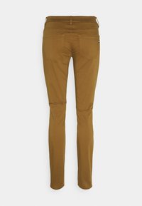 Bruna skinny jeans med en slät textur, diskret sömnad och två bakfickor. Har en midjehöjd med normal resår och en slim fit genom benen.