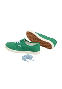Green canvas Vans sneakers with white soles, white laces, gum rubber waffle-patterned outsole, and extra blue laces beside shoes.