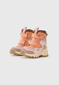 Rosa und beige Knöchelstiefel mit einer robusten Sohle, ausgestattet mit zwei verstellbaren Klettverschlüssen und einem weichen Textiloberteil. Verstärkter Rücken für zusätzlichen Halt.