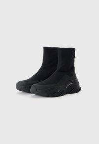 Bottines noires en matériau durable et texturé, avec une épaisse semelle en caoutchouc et un design de contour unique. Fini lisse, détails minimaux.