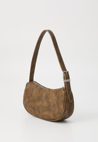Sac à main en simili cuir marron avec une forme arrondie, une bandoulière unique et des détails en zip argenté. Texture lisse avec une finition mate.