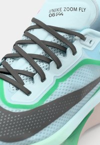 Nike Zoom Fly tenisice imaju svijetloplavu gornjište s mrežastim panelima, sive vezice, zelene i sive naglaske te teksturirani dizajn potplata.