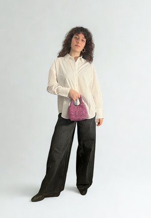 Pantalon large noir épais, chemise blanche boutonnée et petit sac à main rose texturé. Design simple avec des accents minimalistes.