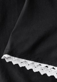 Musta kangas ribbed-tekstuuri, jossa on aallotettu valkoinen pitsireunus helman kohdalla. Yleisilmeeltään sileä, mutta kontrastina koristeellinen reunus.