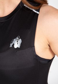 Juodas sportinis tankas, pagamintas iš lygaus audinio, su nedideliu sidabriniu gorilos logotipu šone ir kontrastingu siuvimu palei siūles.
