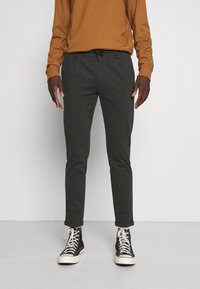Mørkegrå tapered bukser med elastisk talje og snoretræk, parret med sorte high-top sneakers. Stof ser blødt og glat ud.