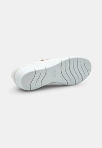 Sneaker bianca con un design testurizzato, suola bianca flessibile con scanalature curve e un logo discreto sulla parte inferiore.
