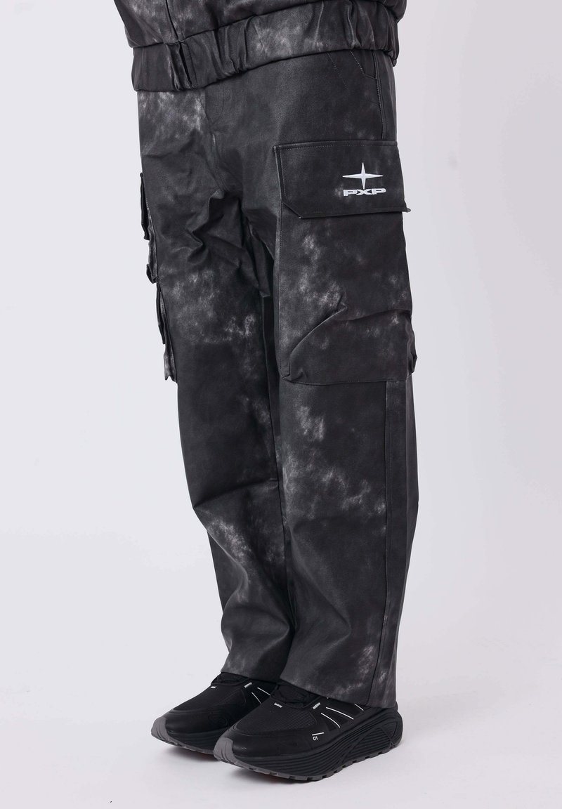 Schwarze Cargo-Hosen mit einem strukturierten, verblassten Muster, elastischem Bund, seitlichen Taschen und einem weißen Logo am Bein, kombiniert mit schwarzen Sneakern.