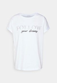Camiseta de algodón blanco con mangas cortas, con texto en purpurina plateada que dice "SIGUE tus sueños" en una mezcla de fuentes.