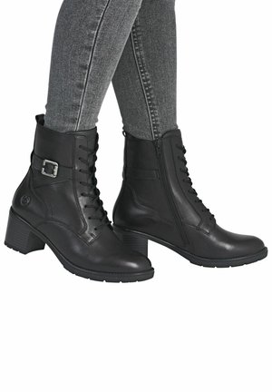 Bottines en cuir noir à lacets à l'avant, avec une fermeture éclair sur le côté et un petit talon carré. Elles présentent une boucle décorative sur le côté extérieur.