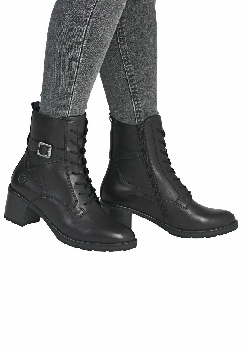 Bottines en cuir noir à lacets à l'avant, avec une fermeture éclair sur le côté et un petit talon carré. Elles présentent une boucle décorative sur le côté extérieur.