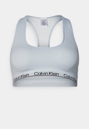 Jasnoniebieski sportowy stanik z tyłem w stylu racerback, o miękkiej fakturze i czarną opaską z logo Calvin Klein na dole.