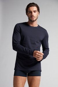 Marineblaues Langarmshirt aus glattem Stoff, mit rundem Halsausschnitt und tailliertem Schnitt. Kombiniert mit dunklen, engen Shorts, minimalistischem Design.
