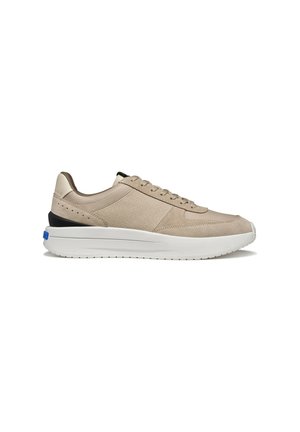 Baskets basses beige avec panneaux latéraux texturés, lacets sur le devant, semelle blanche épaisse et accent noir au talon.