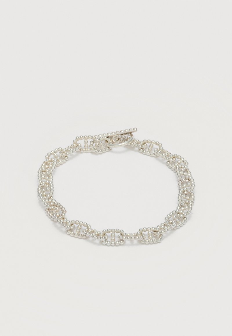 Λεπτό βραχιόλι από μικρές ασημένιες χάντρες συνδεδεμένες σε αλυσιδωτές θηλιές με κούμπωμα τύπου toggle σε λευκό φόντο.