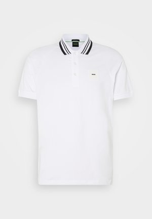 Vit polo skjorta i bomull, med en placket med tre knappar, krage med svart och vit rand, samt en fyrkantig logopatch på bröstet.