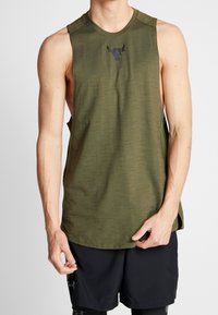 Camisa atlética sin mangas color verde oliva con una tela texturizada, que presenta un logo negro en el pecho y aberturas laterales para la circulación del aire.