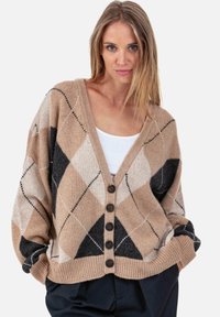 Cardigan argyle beige et marron avec un col en V, coupe ample et cinq boutons marron sur le devant. Texture douce avec des poignets côtelés.