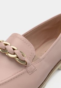 Ανοιχτό ροζ δερμάτινη λευκή με χρυσή αλυσίδα και πλεγμένη λεπτομέρεια στο επάνω μέρος, ορατή ραφή και μπεζ σόλα.