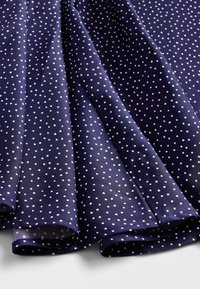 Marineblaue Stoff mit kleinen weißen Polka-Dots, glatter Textur, gefaltete Kanten, leichtes Material, geeignet für Kleidung oder Accessoires.