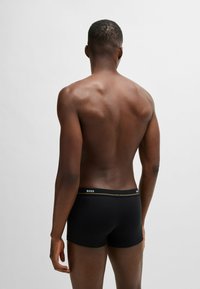 Zwarte boxershorts met een merkband. De stof is glad met een aansluitend ontwerp. Zichtbare naden en een korte pijp.