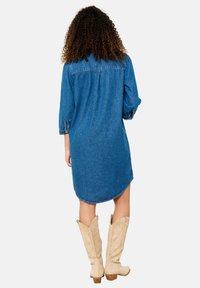 Sininen farkku-shirt mekko, jossa on napitettava etuosa, kä�ärityt hihat ja kaareva helma. Yhdistetty vaaleankremin cowboy-korkokenkiin.