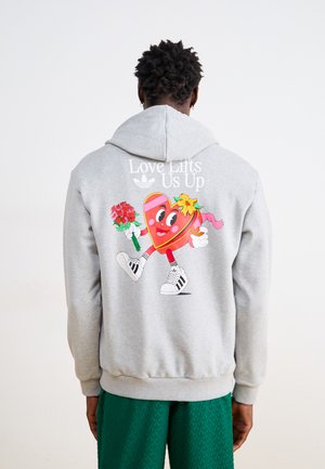 Un sweat à capuche gris clair avec un cœur en dessin animé coloré ayant des bras, tenant des fleurs. Le texte au-dessus dit : "L'amour nous élève." Accents noirs sur les manches.