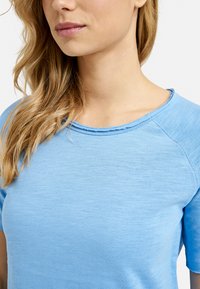 Light blue, short-sleeve shirt made of soft fabric with a round neckline and subtle texture, featuring reinforced seams on shoulders.