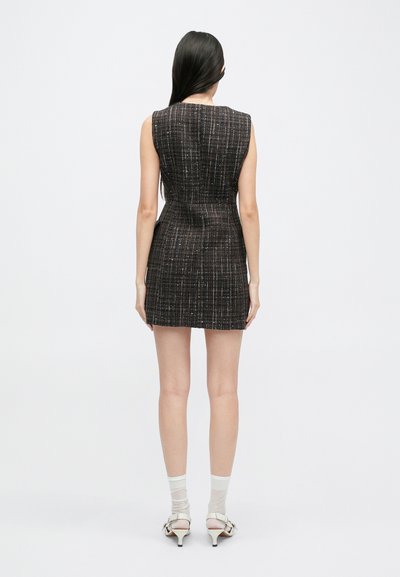 Vestido mini ajustado sin mangas en una tela texturizada oscura con patrones verticales. La vista desde atrás muestra un diseño entallado y un dobladillo corto.