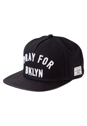 Czarna czapka typu snapback z białym haftowanym napisem "PRAY FOR BKLYN" oraz małą etykietą "Cayler & Sons" z boku.