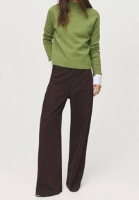 Pull vert à col rond, manches longues et tissu texturé, associé à un pantalon large marron foncé avec une surface lisse et des poches latérales.