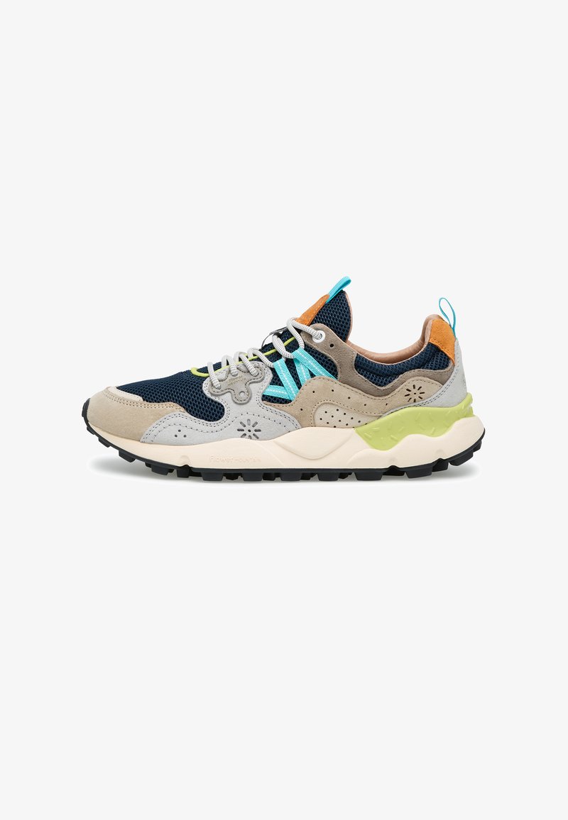 Sportowy sneaker z granatową siateczką, beżowymi zamszowymi nakładkami, jasnoniebieskimi akcentami, białymi sznurowadłami i teksturowaną zielono-białą podeszwą.