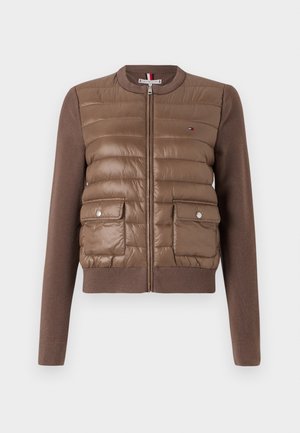 Chaqueta bomber acolchada marrón con cierre de cremallera en la parte delantera, puños y dobladillo acanalados, con dos bolsillos frontales con cierres a presión y un detalle de logo.