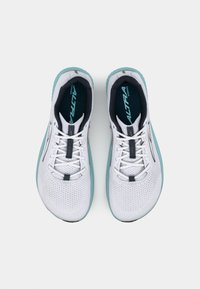 Hvite joggesko med et pustende mesh-overdel, teal-acenteringer på sålen og reflekterende detaljer. Snøring og polstret såle.