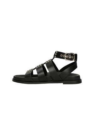 Black leather sandals with multiple horizontal straps, buckle closure, and decorative silver studs. Flat sole with a smooth finish.
